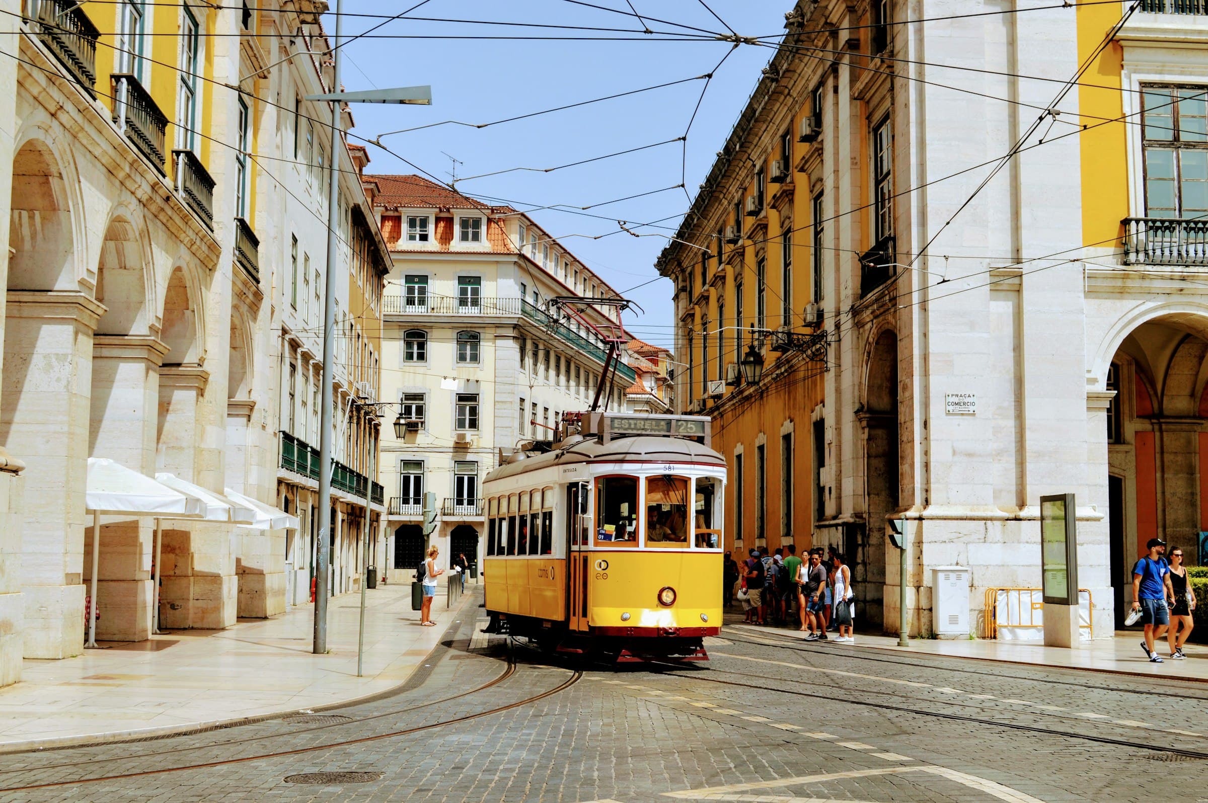 A historic yellow tram on a cobbled street in Lisbon, Portugal